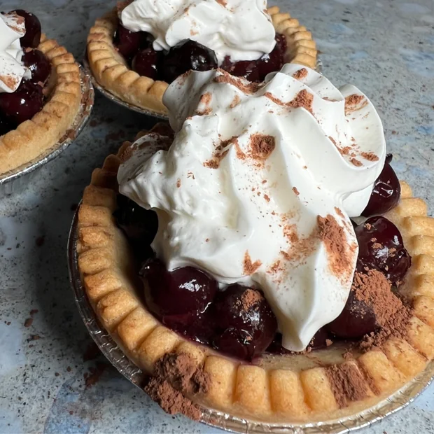 Cherry tarts topped with cream and cocoa